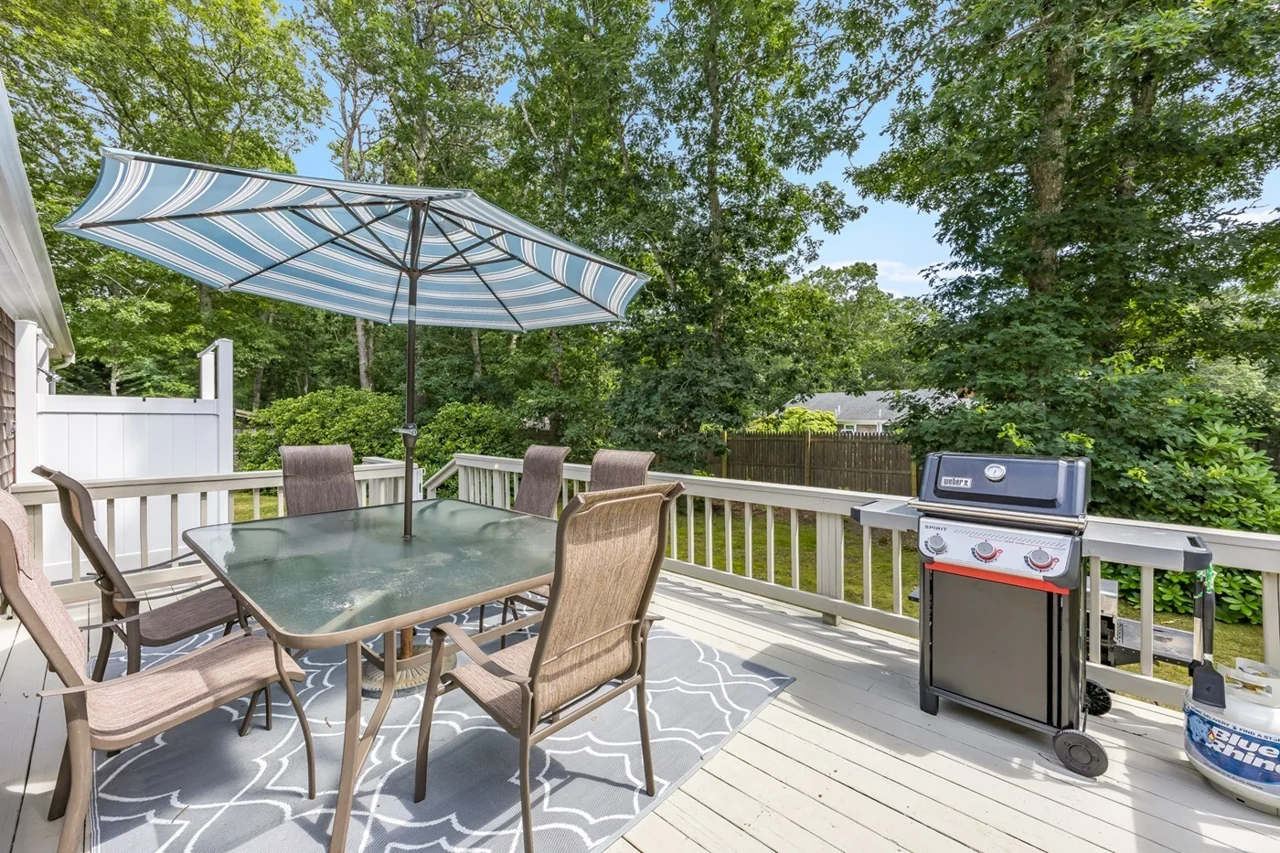 Outdoor deck with a dining table, umbrella and gas grill